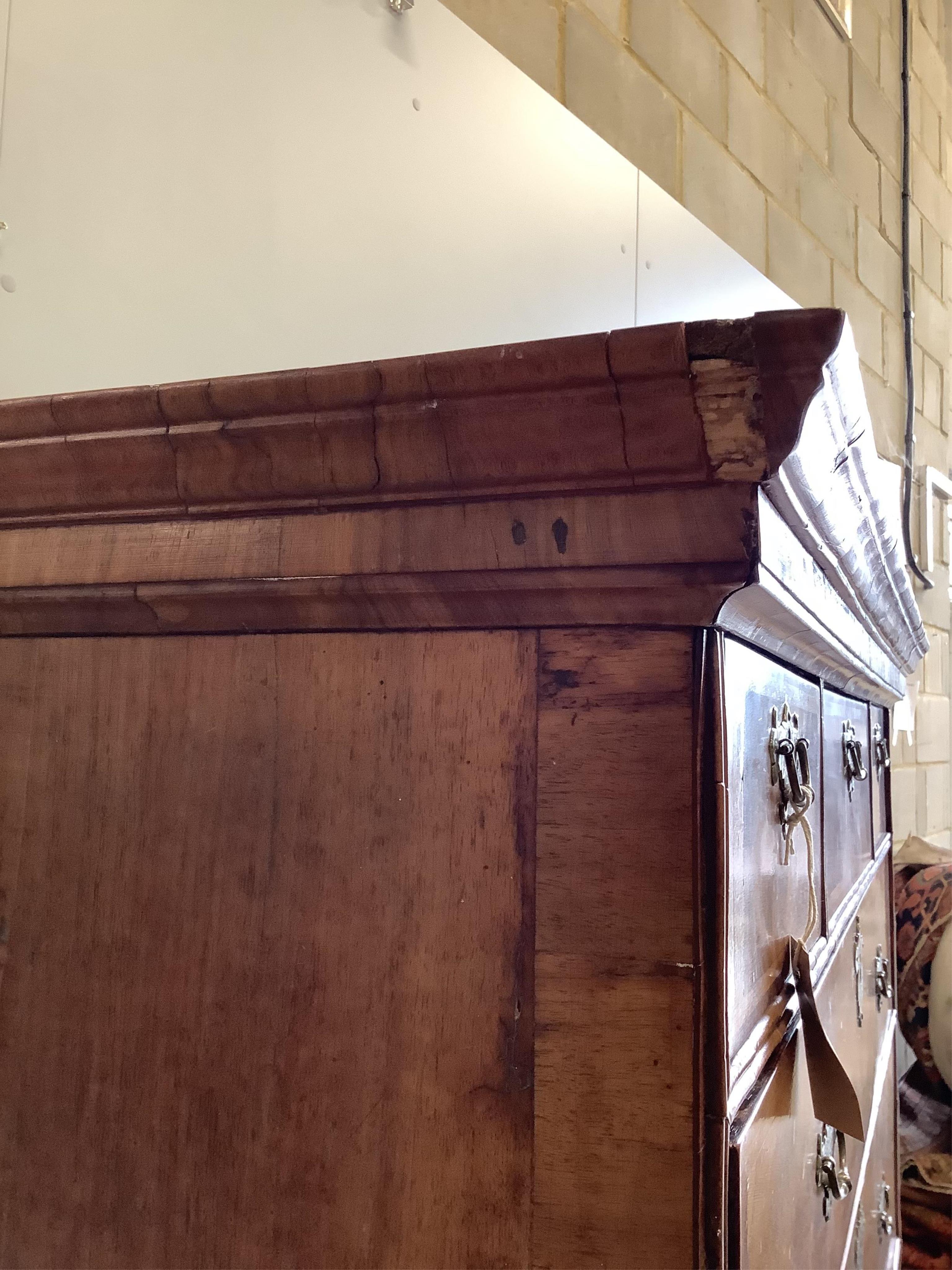 An early 18th century walnut chest on stand with later bun feet, width 106cm, height 147cm. Condition - fair